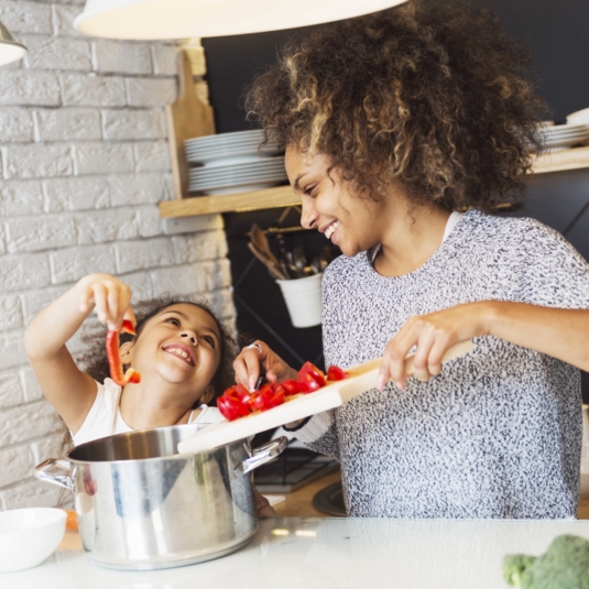 Beautiful African American woman and her daughter cooking in the