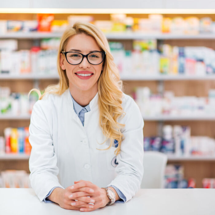 Portrait of a beautiful blonde pharmacist leaning on counter at