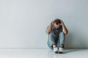 full length view of scared depressed man sitting with hands behi
