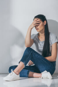 full length view of depressive brunette girl sitting with hand o full length view of depressive brunette girl sitting with hand o